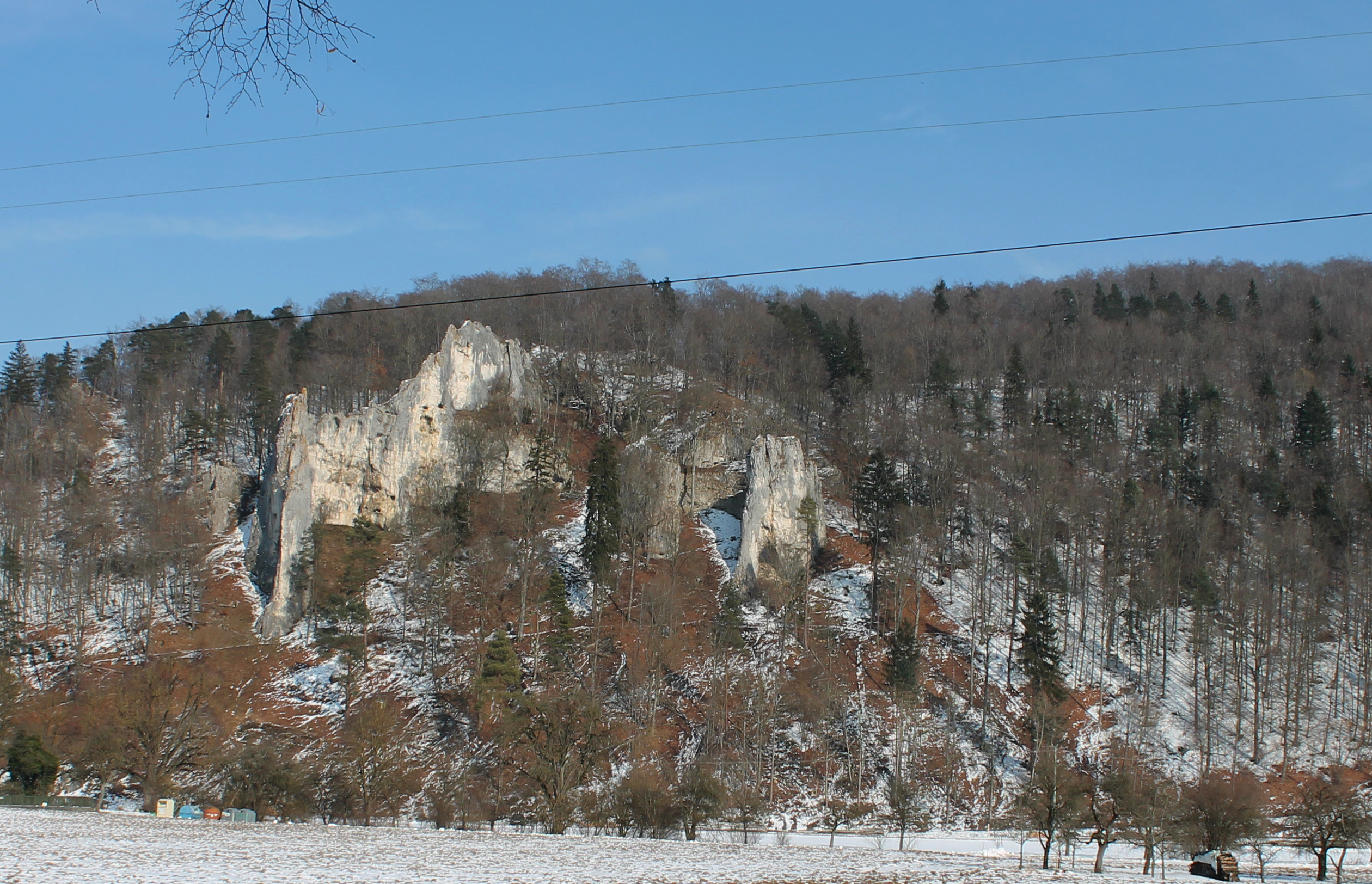 Ein Blick auf die Kalkfelsen von Geißenklösterle (Deutschland) vom Talboden des Achtals.
