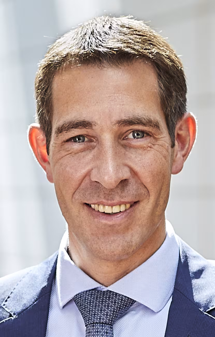 Porträtfoto von Klaus Blaum. Frontalansicht eines Mannes, der den Betrachter anlächelt. Er trägt keine Brille und hat kurze braune Haare.