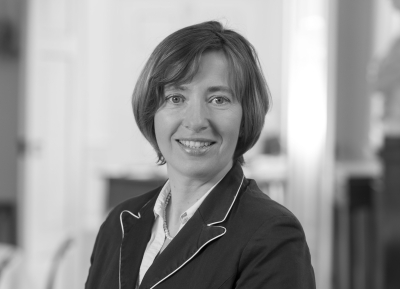 Porträtfoto, das Friederike Busse in zugewandter Pose zeigt. Sie lächelt den Betrachter frontal an und trägt kurze Haare mit Seitenscheitel, die über die Ohren etwa bis zum Kinn reichen. 