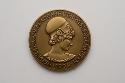 Die Bronzemedaille zeigt den Kopf der Athene als griechischer Göttin der Wissenschaft. Am Rand der Medaille verläuft der Schriftzug Heidelberger Akademie der Wissenschaften 1909.   
