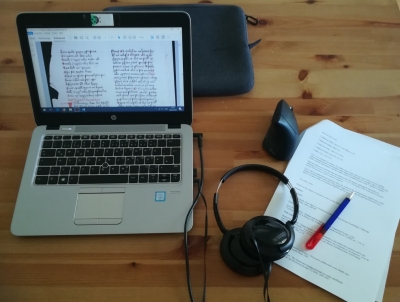 Arbeitsplatz mit Laptop, Headset, Papier und Stift