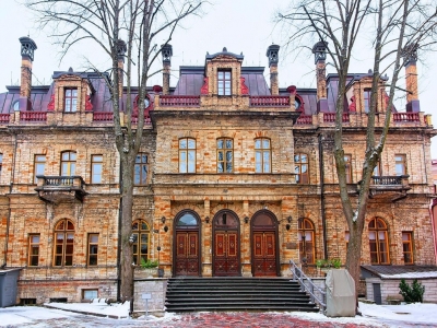 Dreigliedriges dreistöckiges Gebäude mit heller Steinfassade bei leichtem Schnee. Vor dem Mittelrisalit Treppe zu den drei zentralen Eingängen der Estnischen Akademie der Wissenschaften