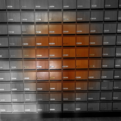 Aufnahme eines Regals voller Karteikästen in mindestens zehn mal zehn Reihen. In der Mitte ist die Aufnahme farbig, die Kästen sind rot-braun gefärbt, am Rand sind sie grau.