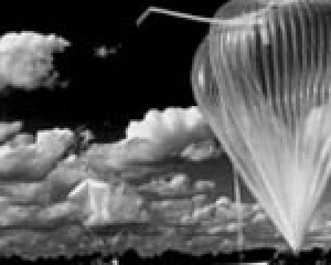 Schwarz-weiß Foto der Vorbereitungen zum Start des ballon-gestützten TDLAS-Spektrometer in Aire sur l’Adour; Ein transparenter Ballon ist vor einem wolkenbehangenen Himmel zu sehen. Der Himmel ist schwarz, der Ballon erscheint wie die Wolken weiß.