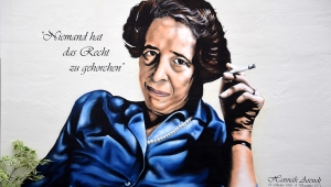 Graffito: BeneR1 und koart an Arendts GeburtshausHannah Arendt, Arendt sitzt in blauer Bluse und mit Zigarette in der Hand da und schaut die Betrachtenden an, neben ihrem Kopf steht "Niemand hat das Recht zu gehorchen"